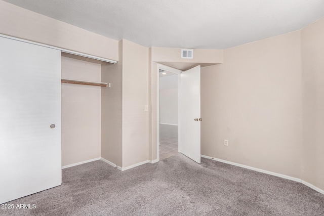 unfurnished bedroom with a closet, visible vents, light carpet, and baseboards