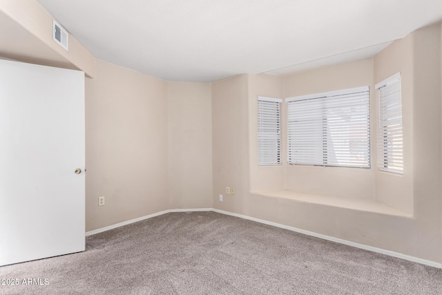 spare room featuring carpet floors, visible vents, and baseboards