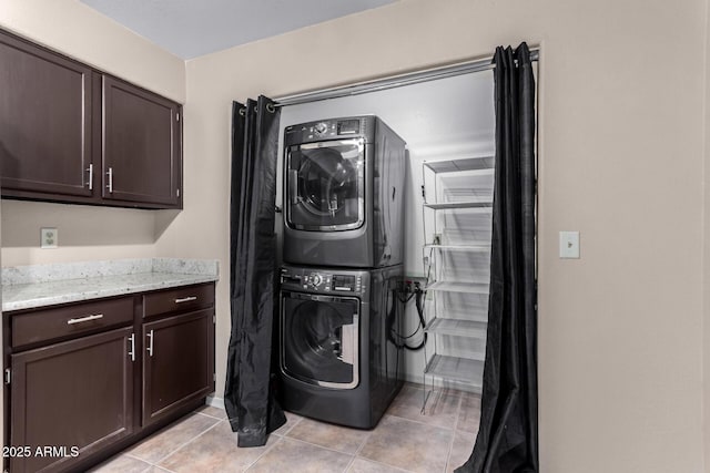 laundry room featuring laundry area, stacked washer / dryer, and light tile patterned flooring