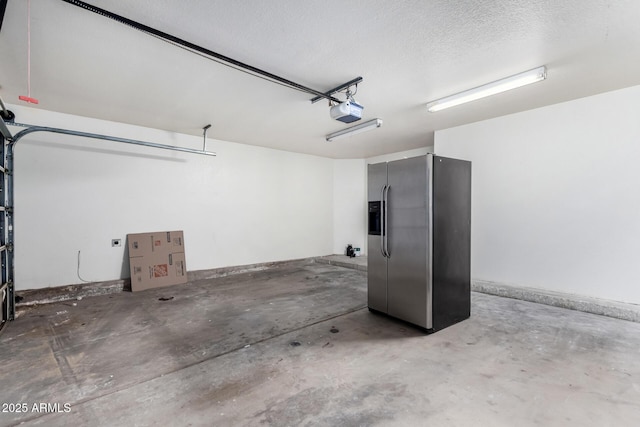 garage with stainless steel refrigerator with ice dispenser and a garage door opener