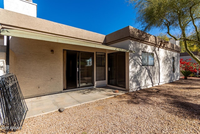 back of property with a patio and stucco siding