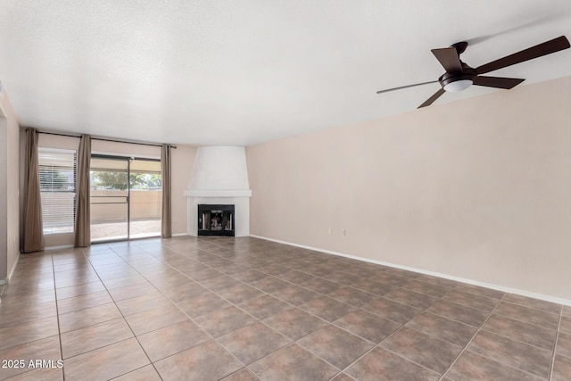 unfurnished living room with a textured ceiling, a fireplace, a ceiling fan, baseboards, and tile patterned floors