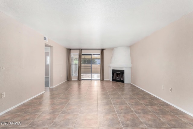 unfurnished living room featuring light tile patterned floors, baseboards, a fireplace, and visible vents