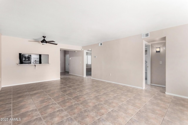 tiled spare room with visible vents, ceiling fan, and baseboards