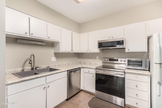 kitchen with light tile patterned flooring, stainless steel appliances, white cabinetry, and sink