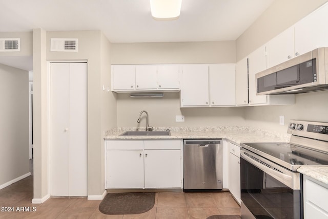 kitchen featuring white cabinetry, sink, light tile patterned floors, and appliances with stainless steel finishes