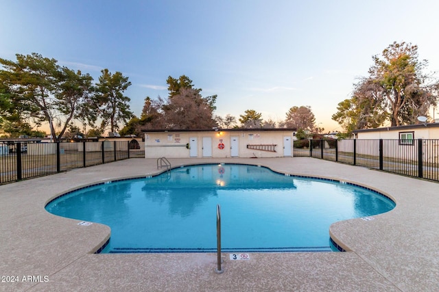 pool at dusk featuring a patio