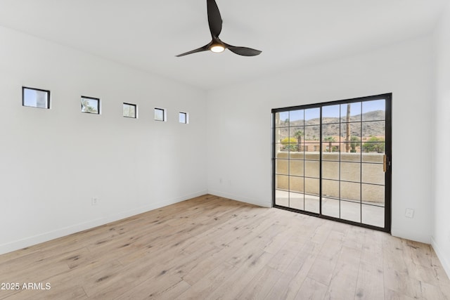 spare room with baseboards, ceiling fan, and wood finished floors