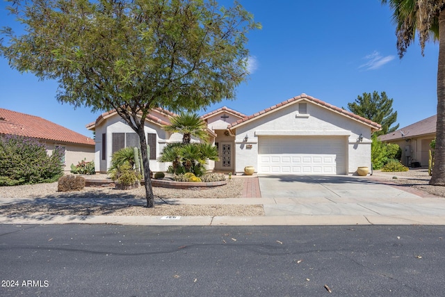 view of front of house featuring driveway, a garage, a tiled roof, and stucco siding