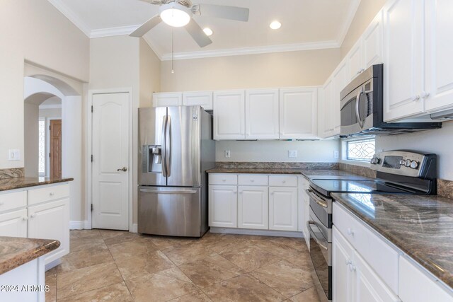 kitchen featuring white cabinetry, appliances with stainless steel finishes, ornamental molding, dark stone countertops, and ceiling fan