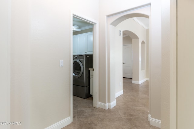 corridor featuring washing machine and dryer, ornamental molding, and light tile patterned floors