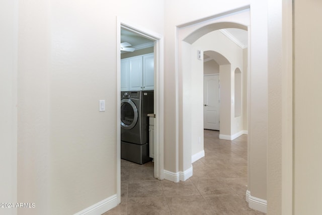 corridor with crown molding, baseboards, light tile patterned flooring, arched walkways, and washer and dryer