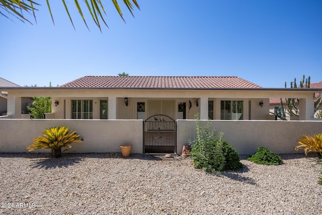 view of front of property with a tiled roof, a fenced front yard, a gate, and stucco siding