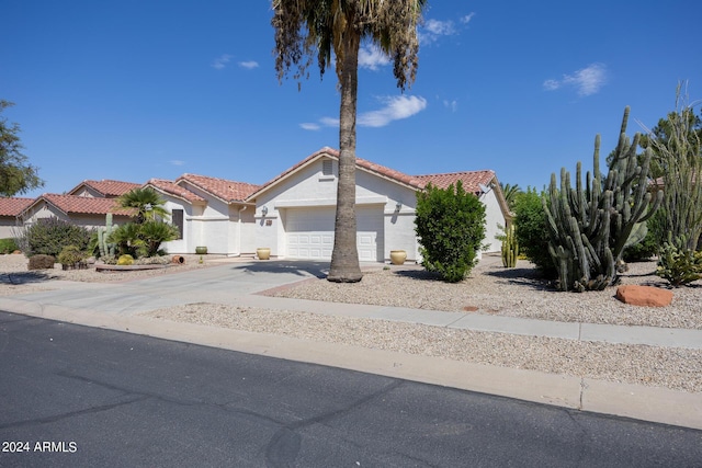 view of front of house with a tile roof, stucco siding, an attached garage, and aphalt driveway