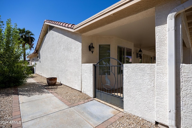 property entrance featuring stucco siding, a gate, and a patio area