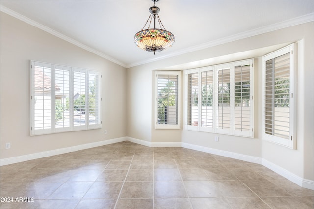 tiled spare room featuring ornamental molding and vaulted ceiling