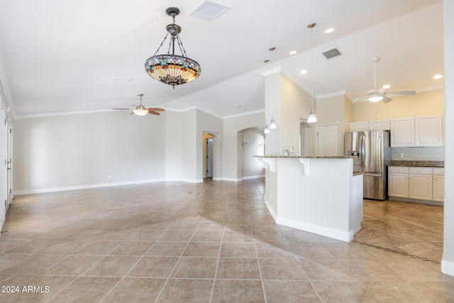 kitchen featuring a kitchen breakfast bar, stainless steel fridge, ornamental molding, and white cabinets