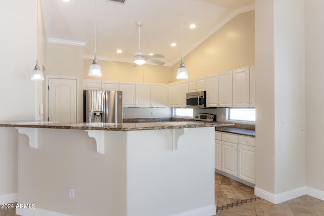 kitchen with white cabinetry, stainless steel appliances, dark stone counters, and a breakfast bar