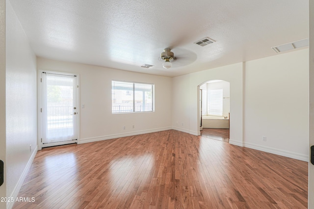 238 W Myrna Ln, Tempe, AZ 85284 - unfurnished room with a ceiling fan, arched walkways, light wood-style flooring, and a textured ceiling