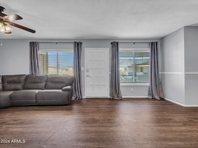 living area featuring baseboards, a ceiling fan, wood finished floors, and a healthy amount of sunlight