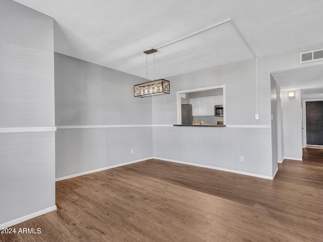 unfurnished dining area with visible vents, baseboards, wood finished floors, and a notable chandelier
