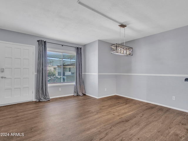 unfurnished dining area featuring an inviting chandelier, baseboards, and wood finished floors