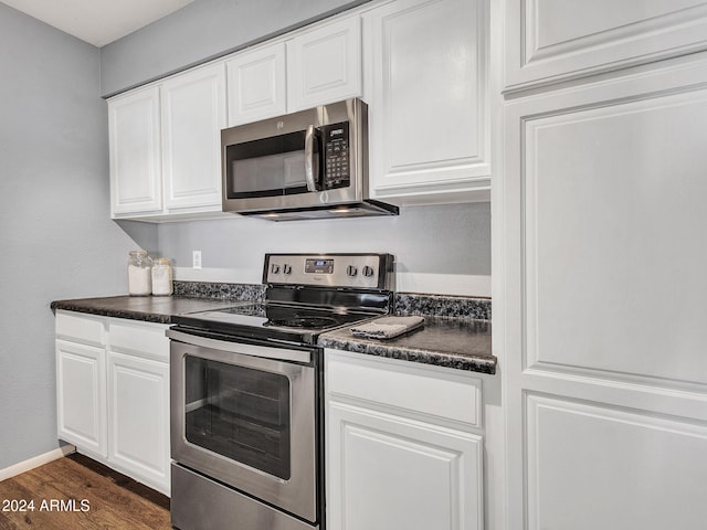 kitchen featuring stainless steel appliances, dark countertops, dark wood-style floors, and white cabinetry