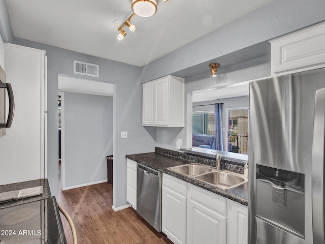 kitchen with visible vents, dark countertops, dark wood-style floors, a sink, and stainless steel appliances