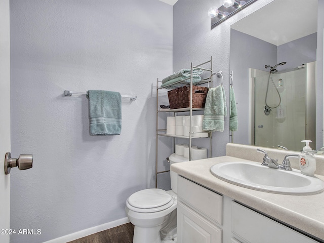 bathroom with vanity, a shower, wood finished floors, toilet, and baseboards