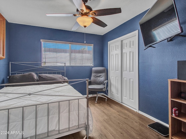 bedroom featuring a ceiling fan, baseboards, wood finished floors, and a closet