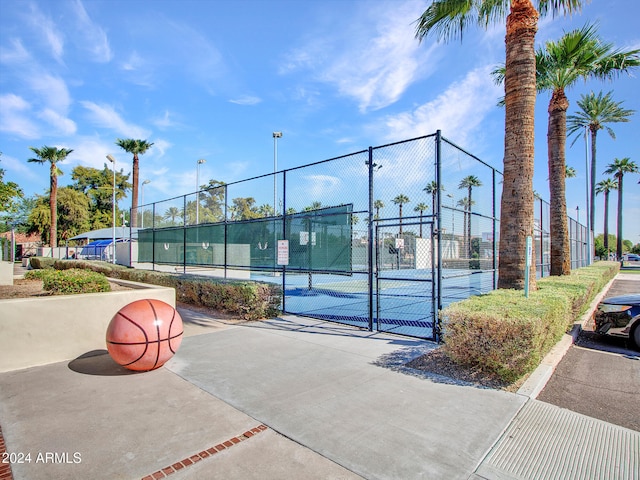 view of tennis court featuring fence and a gate