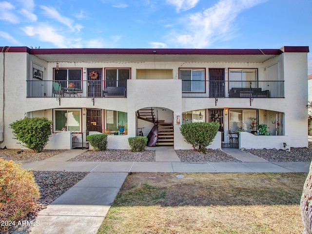view of front of house featuring stucco siding, stairway, and a balcony