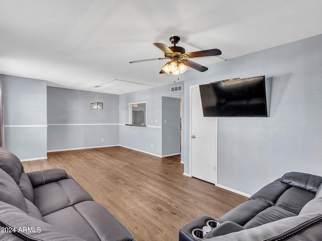 living area with baseboards, ceiling fan, visible vents, and wood finished floors