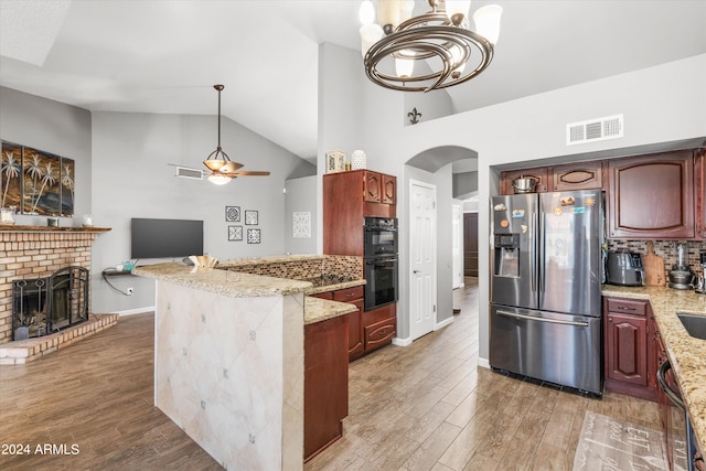 kitchen featuring light stone counters, double oven, stainless steel fridge, and wood-type flooring