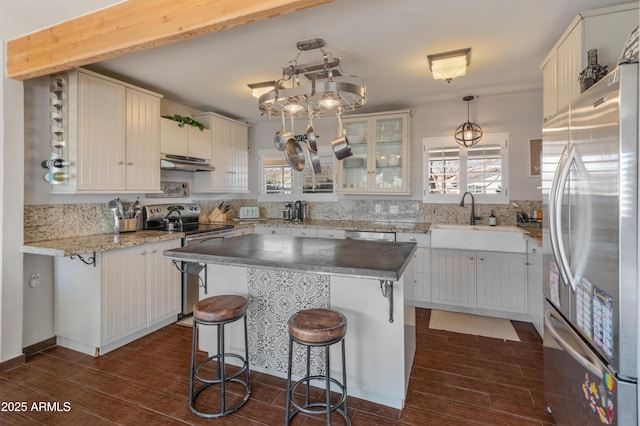 kitchen featuring a center island, a breakfast bar, sink, white cabinetry, and appliances with stainless steel finishes