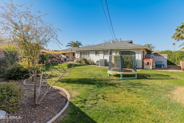 back of house with cooling unit, a storage shed, a lawn, and a trampoline