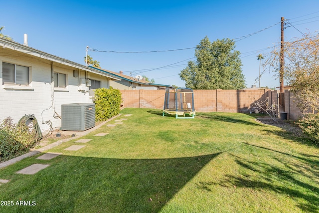 view of yard with a trampoline and central air condition unit