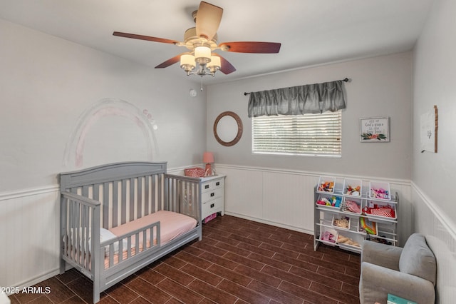 bedroom featuring ceiling fan and a nursery area