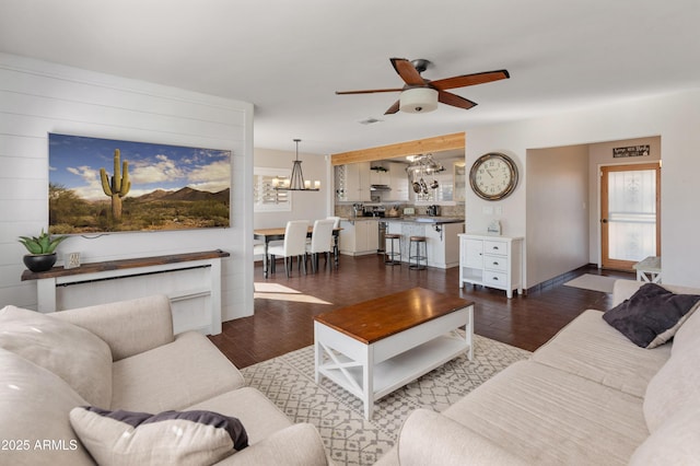 living room featuring dark hardwood / wood-style flooring and ceiling fan with notable chandelier