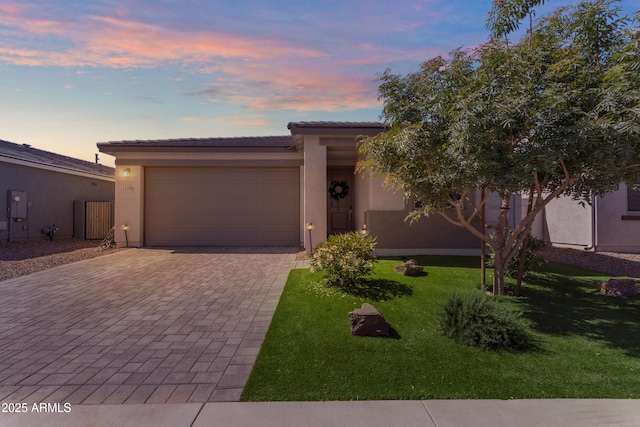 view of front of home with a front lawn, decorative driveway, stucco siding, an attached garage, and a tile roof