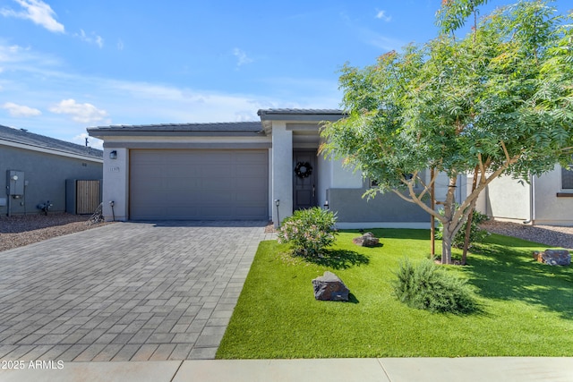 view of front facade with a garage, decorative driveway, stucco siding, and a front yard