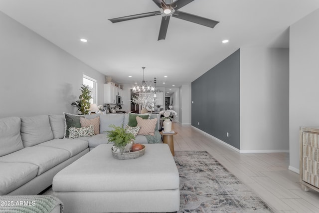 living room featuring recessed lighting, baseboards, and ceiling fan with notable chandelier