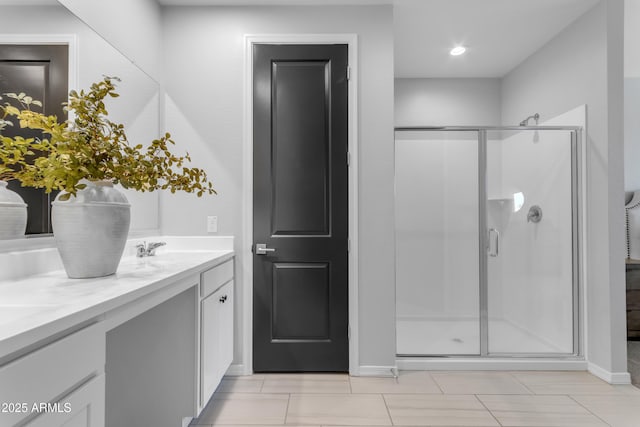 full bath with double vanity, baseboards, a shower stall, and a sink