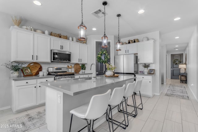kitchen featuring a kitchen island with sink, a breakfast bar area, a sink, stainless steel appliances, and recessed lighting