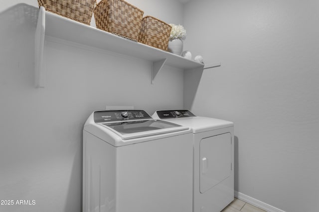 washroom with independent washer and dryer, light tile patterned floors, laundry area, and baseboards