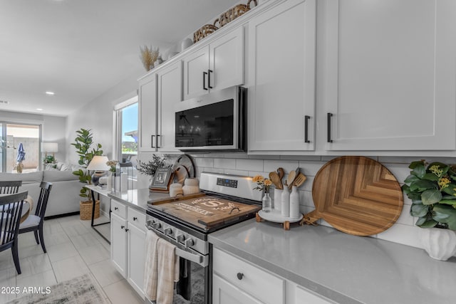 kitchen with tasteful backsplash, light countertops, white cabinets, stainless steel appliances, and recessed lighting