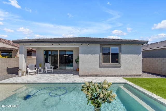 rear view of house featuring an outdoor pool, a fenced backyard, a patio area, and stucco siding