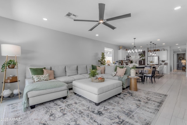 living room with ceiling fan with notable chandelier, recessed lighting, and visible vents