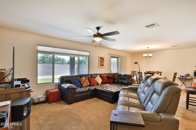 carpeted living room featuring ceiling fan with notable chandelier