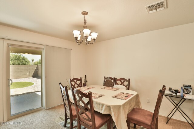 carpeted dining space with an inviting chandelier